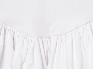 Close-up of white halter mini dress showing knit texture and layered pleated stitching