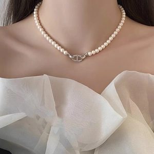 Détail du collier de perles avec fermoir ancre serti de diamants porté par un mannequin