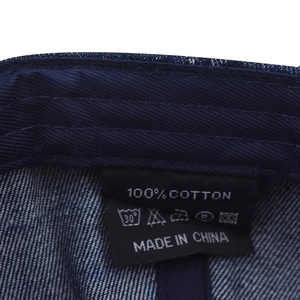 Detail view of the 100% cotton wash label and denim texture on the baseball cap