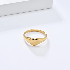 Macro shot of polished gold-finished heart signet ring with a smooth metallic surface