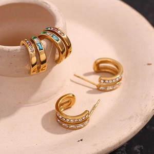 18K gold plated double C-shaped earrings with sparkling cubic zirconia on beige ceramic