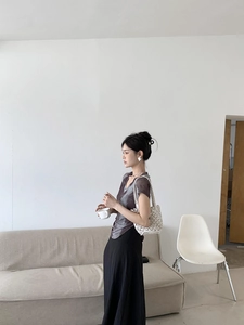 Detail of grey tie-dye V-neck mesh top and black high-waist maxi skirt on model