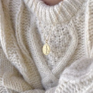925 sterling silver gold plated Mary medallion necklace over a cream knit sweater