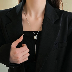 Detail of silver snake chain necklace with round white pearl and elegant Y-shaped tassel