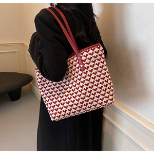 Detail of red heart pattern tote bag with leather strap shown on shoulder by model