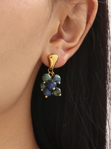 Close-up of gold stainless steel stud earrings with tiger eye and blue marble beads