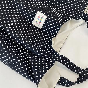 Close-up of black and white polka dot canvas tote bag texture with brand textile label