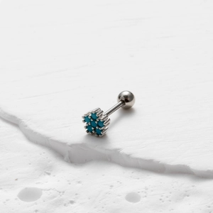 Close-up of a silver stainless steel stud earring with a turquoise flower star pattern