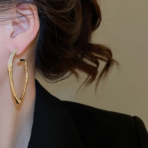 Close-up of golden bamboo-style hoop earrings with sparkling rhinestones on the model