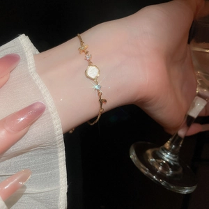 Detailed view of gold ocean charms bracelet with zircon starfish and shell on a female wrist