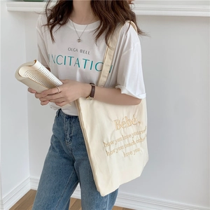 Detailaufnahme der cremefarbenen Segeltuchtasche mit gelber Textstickerei auf der Front