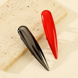 Set de pinzas para el pelo rojas y negras brillantes sobre soporte de piedra