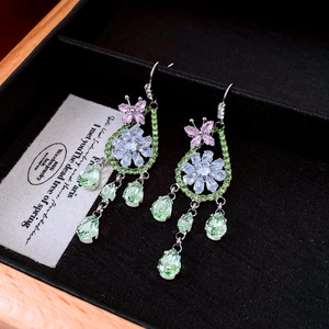Détail des boucles d'oreilles fleurs et papillons avec cristaux roses et pierres vertes