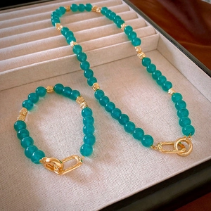 Vintage green beaded necklace and bracelet set with golden rings in a jewelry box