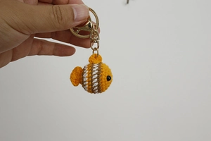 Close-up of handmade crochet clownfish keychain with orange and white yarn details