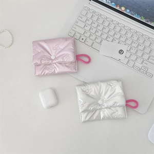 Quilted bow pouches in pink and silver with button closure on a minimalist desk