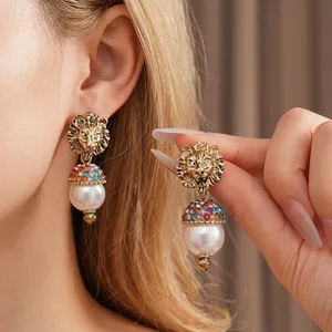 Vintage lion head earrings with sparkling rhinestones and white pearl drops in gold