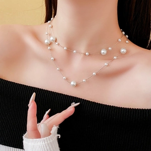 Close-up of double-layer vintage pearl necklace with gold-plated chain worn by a model