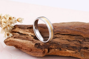 Vue macro d'une bague en acier bicolore poli sur bois avec des fleurs séchées blanches