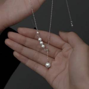 Detailed shot of silver-tone bracelet with white gradient pearls on a hand model