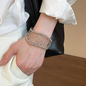 Detail of silver woven mesh cuff bracelet featuring delicate beads on a female model