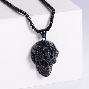 Gothic black skull pendant necklace with embossed vortex patterns on white block