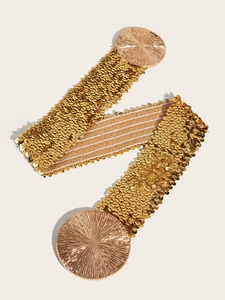 Macro detail of elastic gold sequin belt featuring textured circular metal buckles