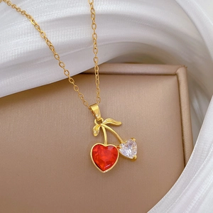 Gold cherry necklace with red and crystal heart pendants on white silk background