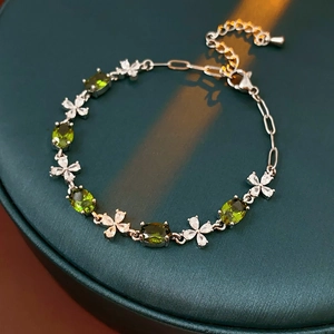 Macro detail of olive green oval zircon bracelet with silver floral accents on green base
