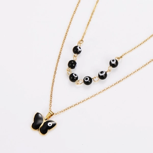 Close-up of gold double-layer necklace with black evil eye beads and butterfly pendant