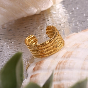 Gros plan d'une bague dorée multicouche texturée sur surface humide avec décor marin naturel