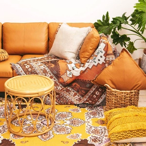 Detail of bohemian geometric woven blanket with tassels on a leather sofa in warm tones