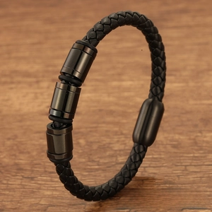 Close-up of black braided leather bracelet with magnetic clasp on dark wood background