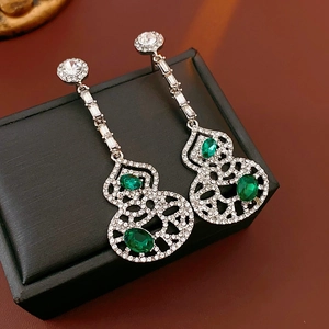 Detail of hollow gourd earrings featuring green emerald-like gems and pavé crystals