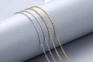 Detail of gold and silver O-shape cable chain necklaces on a gray display stand