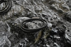 Nahaufnahme eines schwarzen Lederarmbands mit Magnetverschluss auf dunklem Felsuntergrund