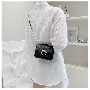 Detail of black quilted chain bag with gold pearl lock and elegant pearl shoulder strap
