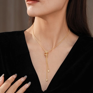 Detailed view of gold Y-shaped fringe necklace with interlocking rings and heart charms