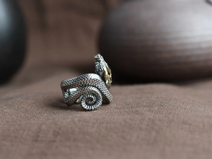 Macro shot of vintage silver snake ring with golden eye detail and textured scales