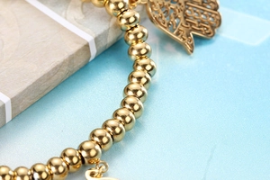 Macro shot of gold beaded stretch bracelet featuring a detailed Hamsa hand pendant