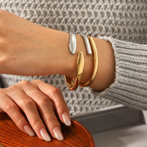 Minimalist two-tone silver and gold stainless steel open bangle worn by a model
