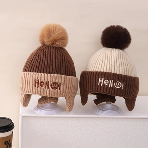 Detailed view of kids winter knit hats with fluffy pom poms and Hello embroidery