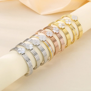 Détail de bracelets trèfle avec nacre et sertissage de cristaux sur métal poli
