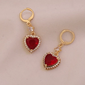 Close-up of gold heart earrings with red gemstones and sparkling crystal details