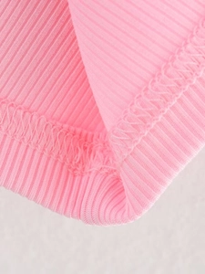 Macro shot of pink ribbed knit fabric showing detailed double-stitching on the hemline