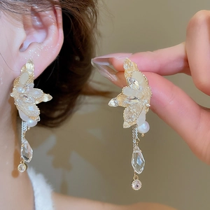Detail of elegant gold tassel earrings with crystal wings and freshwater pearls