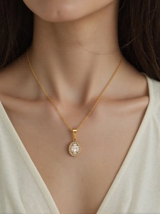 Dettaglio di una collana d'oro con pendente a halo ovale e cristalli bianchi su modella