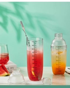Detail of transparent cocktail shaker with black scale markings and mixing tool