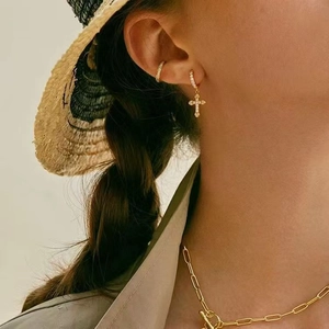 Detail of gold cross earrings and chunky T-bar chain necklace on a model