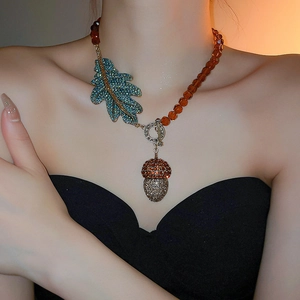 Détail d'un collier vintage avec pendentif gland et feuilles en cristal bleu sur perles ambre